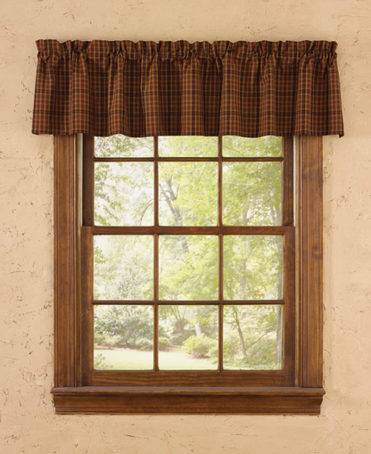 Window with brown plaid valance and wooden frame on a beige wall
