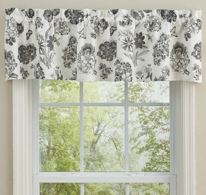 Floral patterned curtain valance above a window with greenery outside