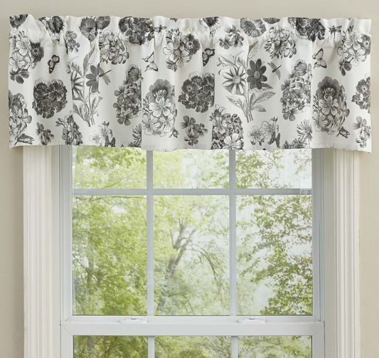 Floral patterned curtain valance above a window with greenery outside
